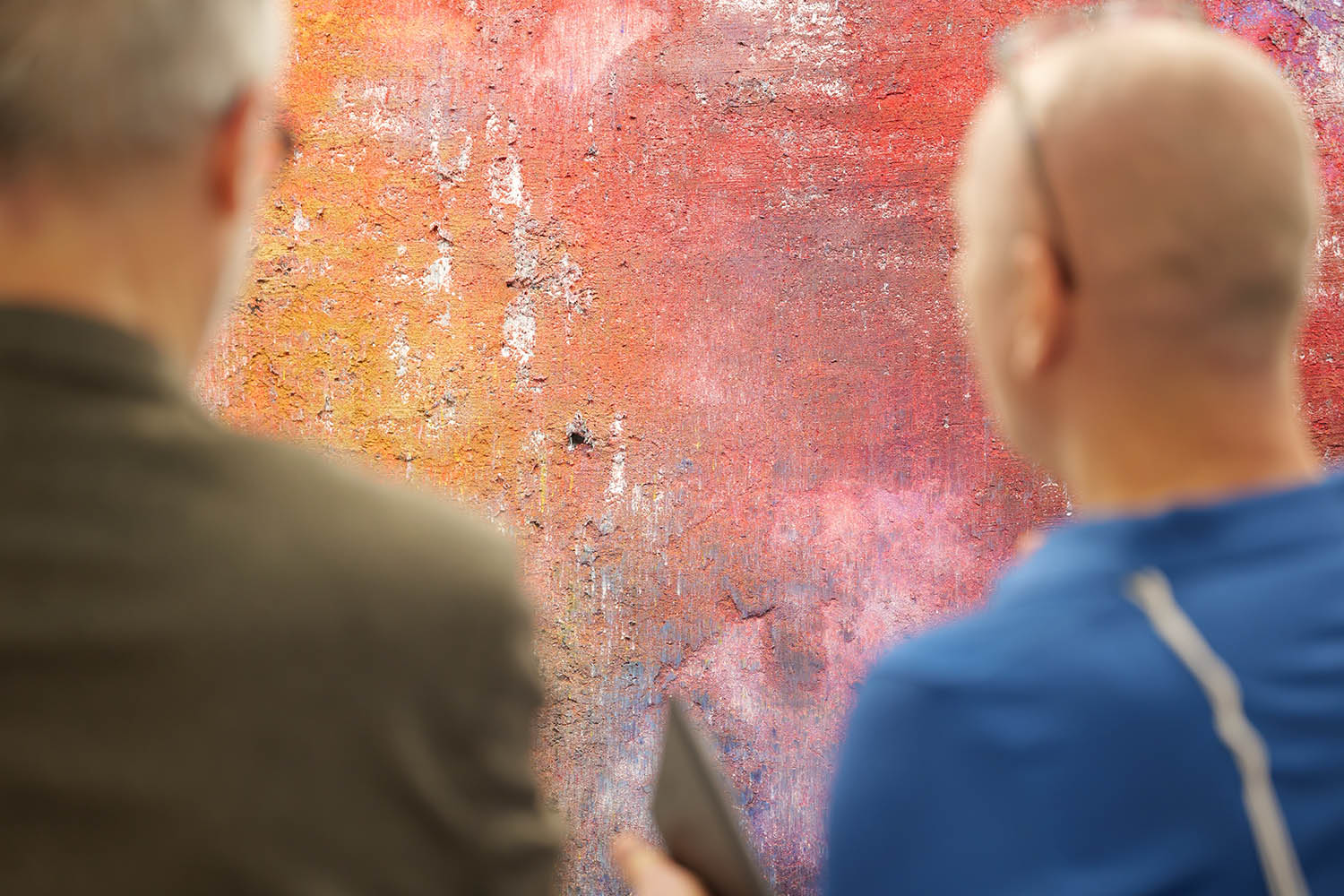 zwei Männer stehen vor einem Kunstwerk und unterhalten sich