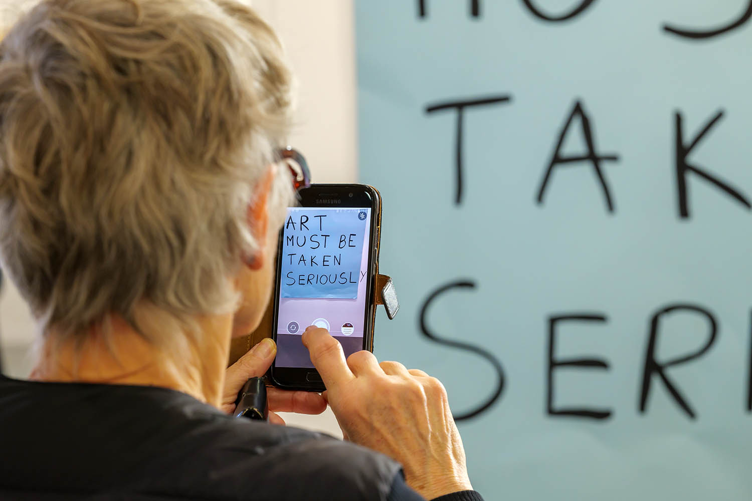 Frau fotografiert Plakat auf der art Karlsruhe